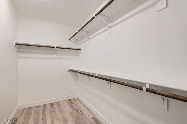 walk in closet with light hardwood / wood-style floors