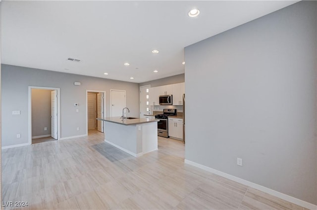 kitchen featuring an island with sink, sink, appliances with stainless steel finishes, and white cabinets