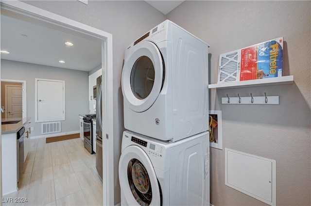 clothes washing area featuring sink and stacked washer / dryer