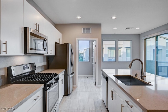 kitchen with plenty of natural light, sink, stainless steel appliances, and white cabinetry