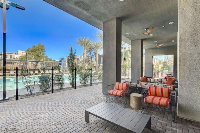 view of patio with an outdoor living space, ceiling fan, and a community pool