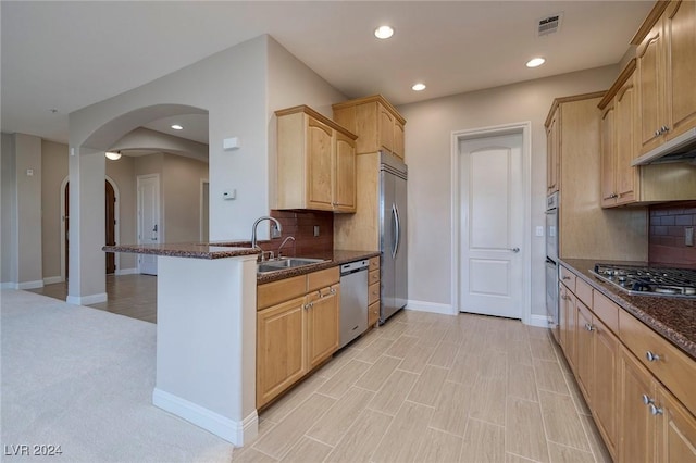 kitchen featuring dark stone countertops, decorative backsplash, sink, and stainless steel appliances