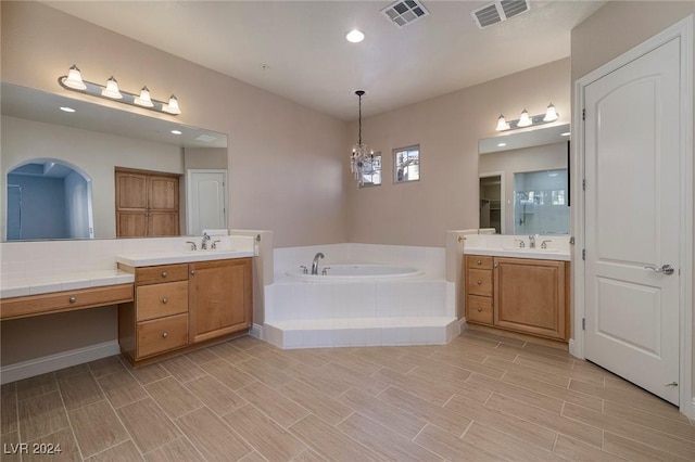 bathroom with tiled bath, vanity, and an inviting chandelier