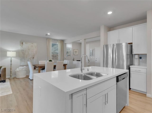 kitchen featuring white cabinets, sink, stainless steel appliances, and an island with sink