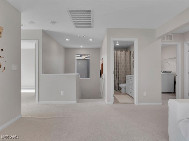 hallway with light colored carpet and washer / clothes dryer