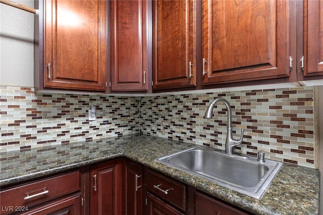 kitchen featuring dark stone countertops, sink, and backsplash