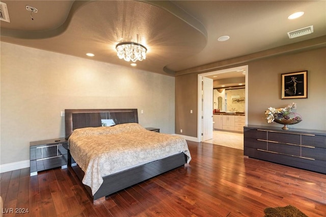 bedroom featuring ensuite bathroom, dark wood-type flooring, and a notable chandelier