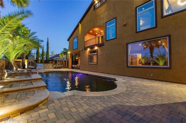 pool at dusk featuring a patio area