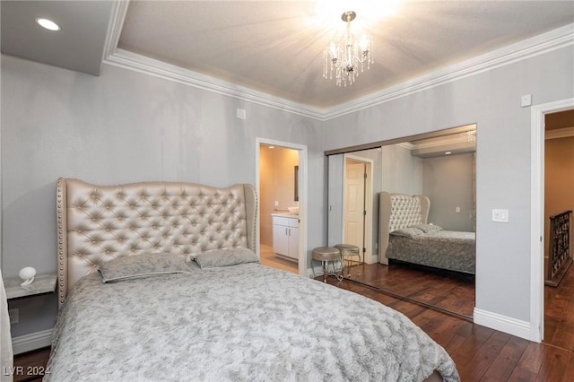 bedroom with dark hardwood / wood-style flooring, crown molding, a notable chandelier, connected bathroom, and a closet