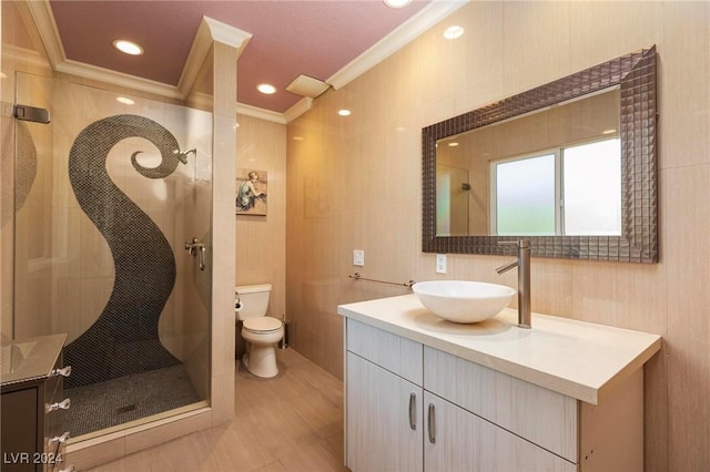 bathroom featuring crown molding, tiled shower, toilet, vanity, and tile walls