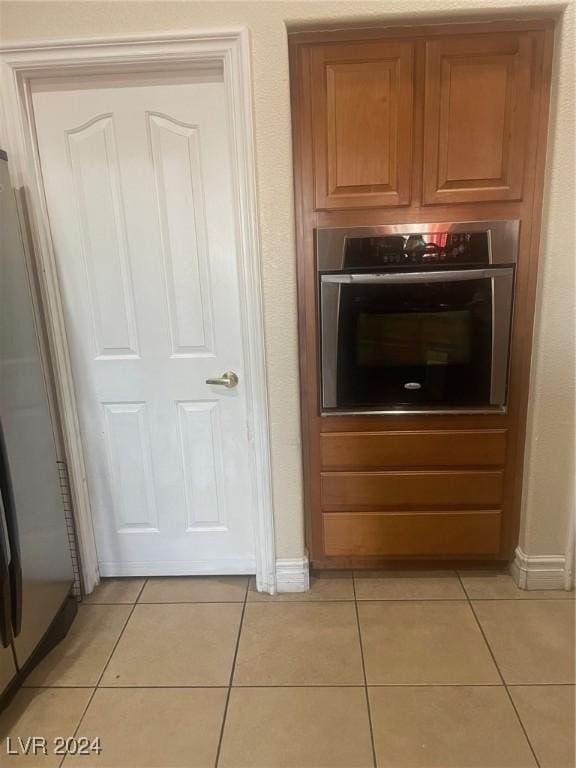 kitchen with stainless steel oven, refrigerator, and light tile patterned floors