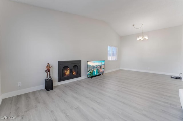 unfurnished living room featuring a chandelier, light hardwood / wood-style flooring, and lofted ceiling