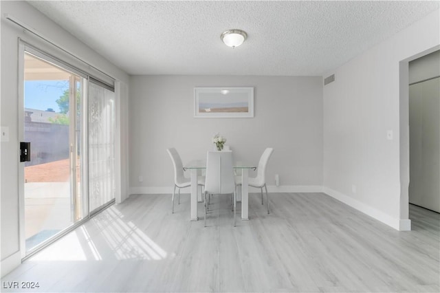 unfurnished dining area with light hardwood / wood-style flooring and a textured ceiling