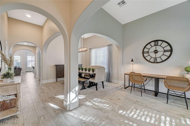 interior space with light hardwood / wood-style floors, a high ceiling, and a notable chandelier