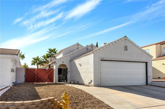 view of front of house with a tile roof, stucco siding, a gate, a garage, and driveway