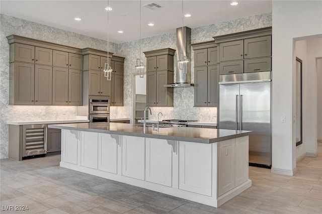 kitchen featuring a kitchen breakfast bar, a spacious island, wall chimney range hood, appliances with stainless steel finishes, and beverage cooler