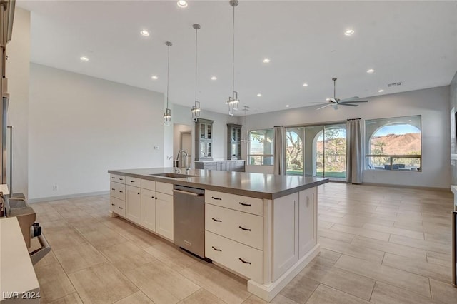 kitchen with dishwasher, a center island with sink, sink, hanging light fixtures, and ceiling fan