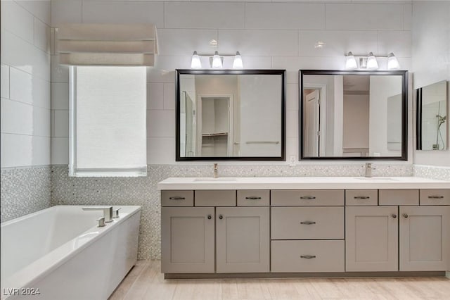 bathroom featuring a bath, vanity, and tile walls