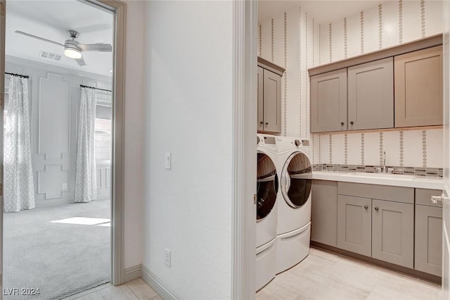 clothes washing area with ceiling fan, sink, cabinets, light colored carpet, and washer and clothes dryer