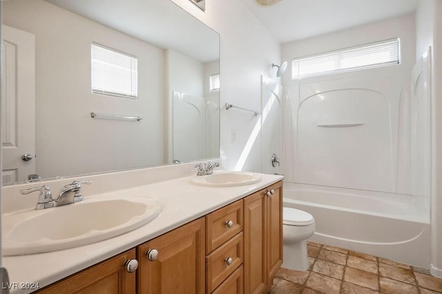 bathroom with double vanity, washtub / shower combination, toilet, and a sink