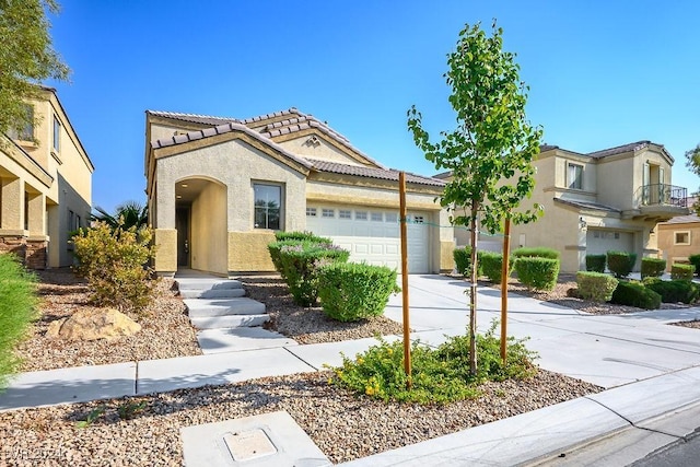 mediterranean / spanish house featuring stucco siding, driveway, a tile roof, and a garage