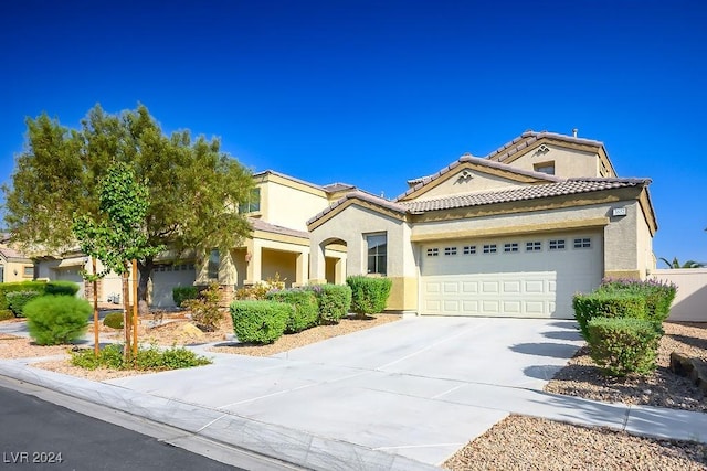 mediterranean / spanish-style home with stucco siding, a garage, concrete driveway, and a tile roof