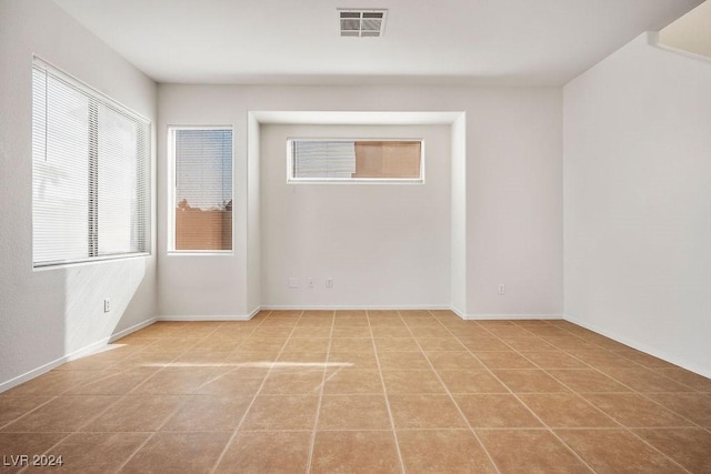 unfurnished room with light tile patterned flooring, baseboards, and visible vents