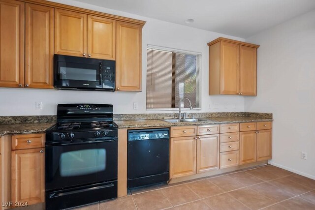 kitchen with light tile patterned flooring, sink, dark stone countertops, and black appliances