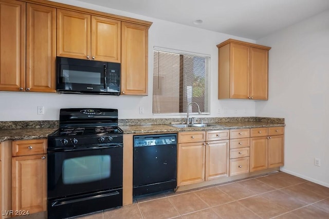 kitchen with dark stone countertops, light tile patterned floors, baseboards, a sink, and black appliances