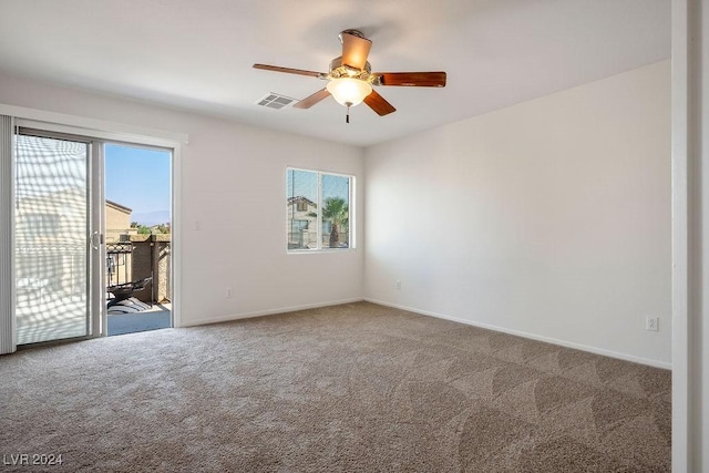 carpeted spare room with baseboards, visible vents, and ceiling fan