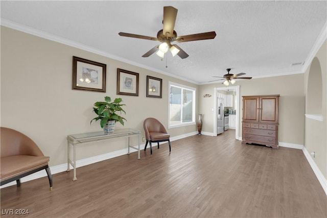 sitting room featuring a textured ceiling, ceiling fan, wood-type flooring, and crown molding