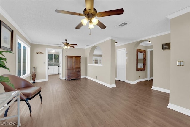 living room with a textured ceiling, ceiling fan, ornamental molding, and dark wood-type flooring