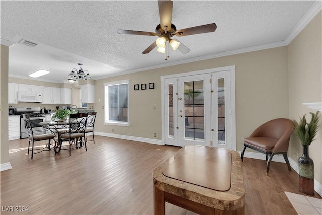 living room featuring crown molding, ceiling fan with notable chandelier, light hardwood / wood-style floors, and a textured ceiling