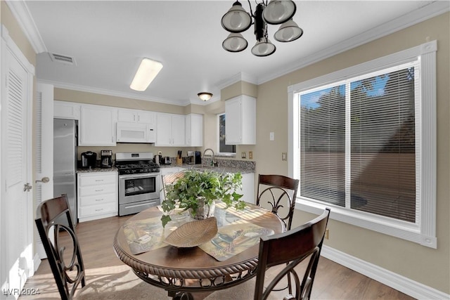 dining area featuring a chandelier, hardwood / wood-style floors, ornamental molding, and sink