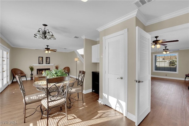 dining space featuring a tile fireplace, light wood-type flooring, and ornamental molding