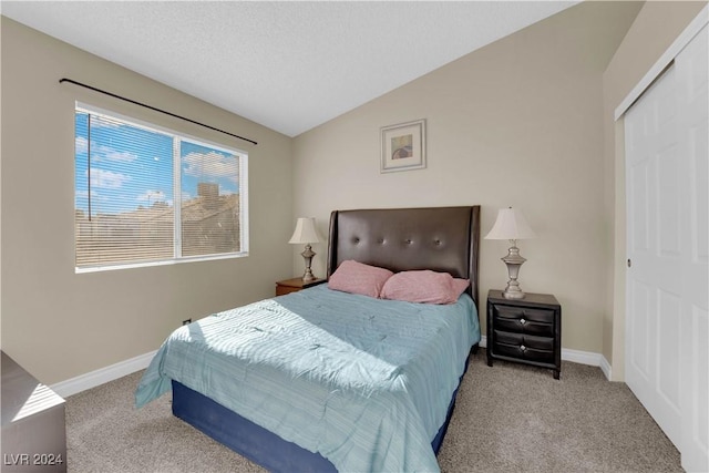 bedroom featuring light carpet, vaulted ceiling, and a closet