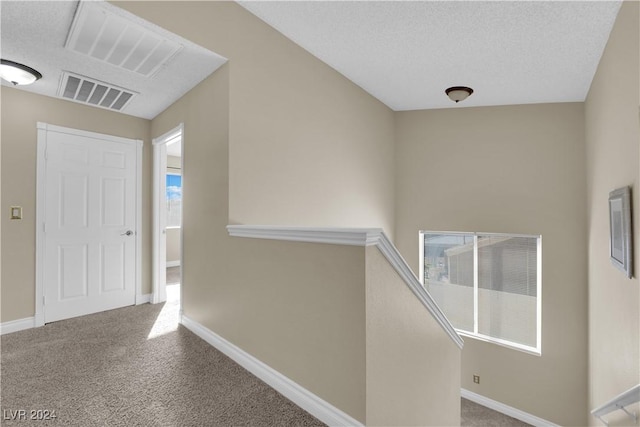 corridor featuring carpet flooring and a textured ceiling