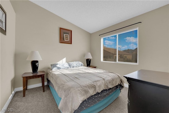 carpeted bedroom with a textured ceiling and vaulted ceiling