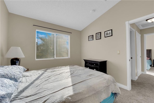 bedroom with a textured ceiling, light colored carpet, and vaulted ceiling