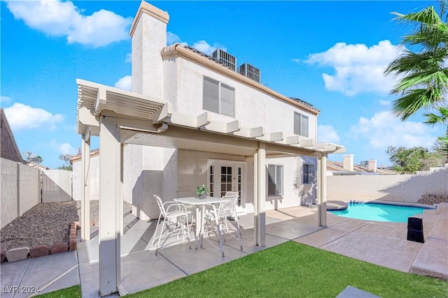 rear view of property featuring a fenced in pool and a patio area