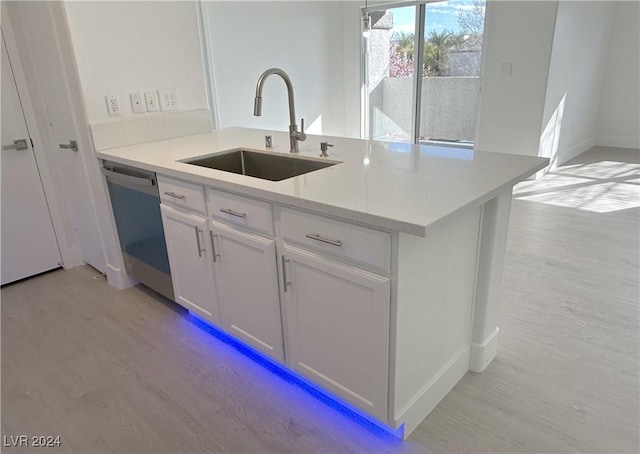 kitchen with light stone counters, a sink, white cabinetry, light wood-style floors, and dishwasher