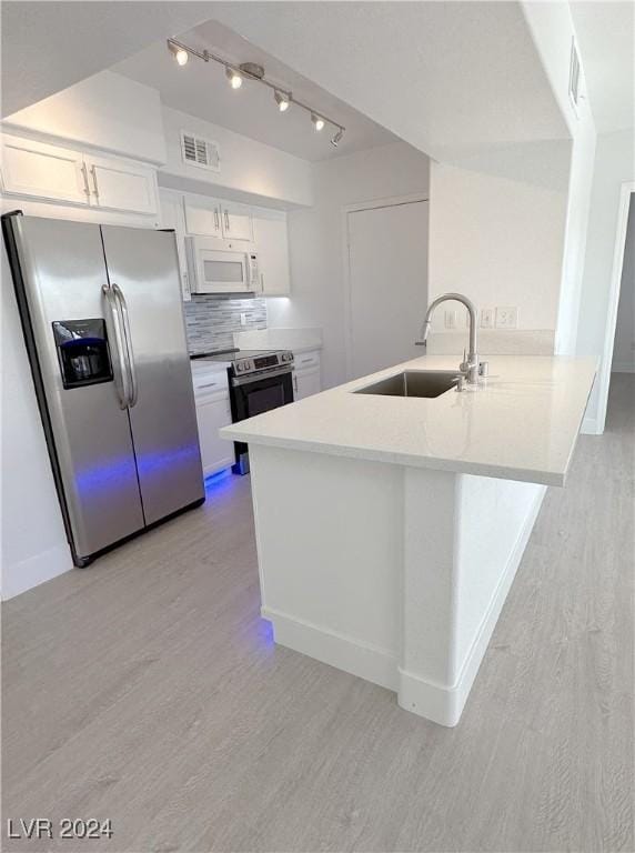 kitchen featuring light wood finished floors, white cabinets, a peninsula, stainless steel appliances, and a sink