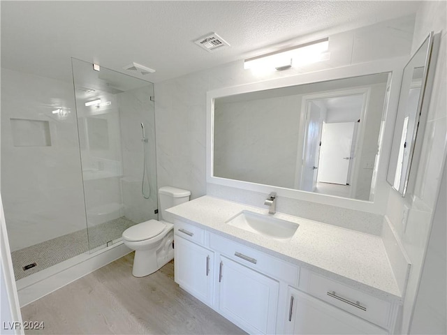 full bathroom with toilet, a stall shower, a textured ceiling, vanity, and wood finished floors