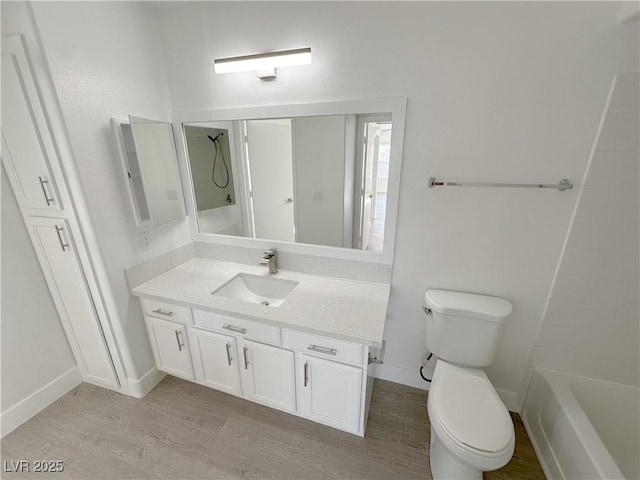 bathroom with toilet, baseboards, wood finished floors, and vanity