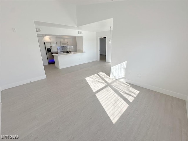 7255 W Sunset Rd Unit 2046, Las Vegas, NV 89113 - unfurnished living room featuring light wood finished floors and high vaulted ceiling