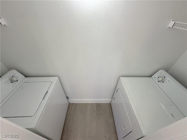 washroom with laundry area, washer / clothes dryer, wood finished floors, and visible vents