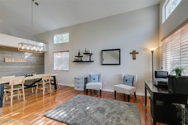 home office with wood walls, wood-type flooring, and a high ceiling