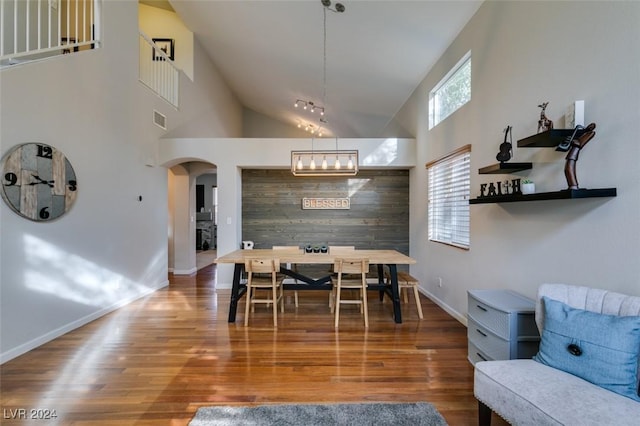 dining area featuring wood-type flooring and a towering ceiling