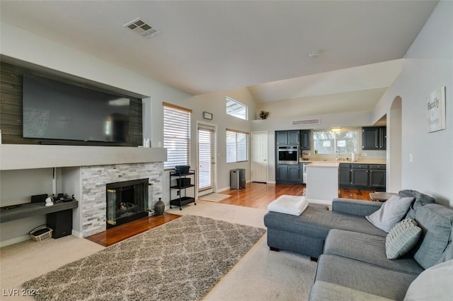 living room featuring a fireplace, lofted ceiling, and sink