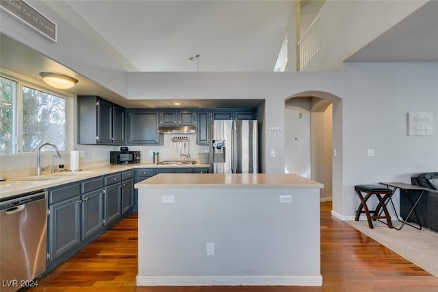 kitchen featuring blue cabinetry, a center island, sink, stainless steel appliances, and wood-type flooring